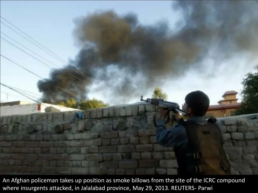 an afghan policeman takes up position as smoke