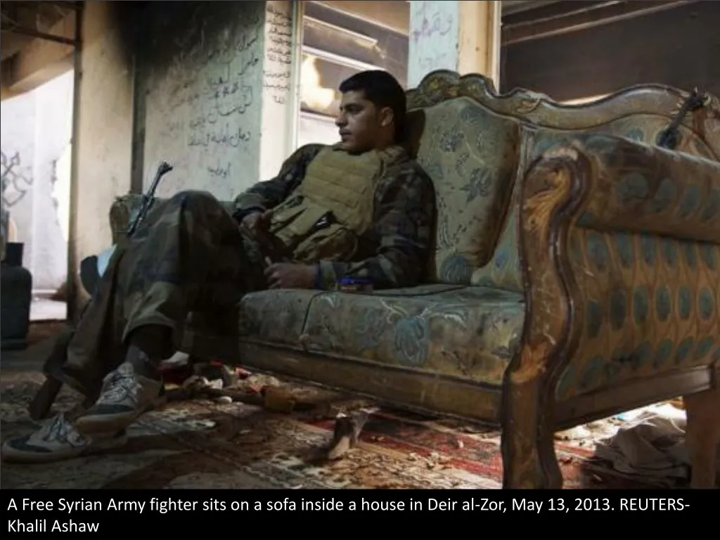 a free syrian army fighter sits on a sofa inside