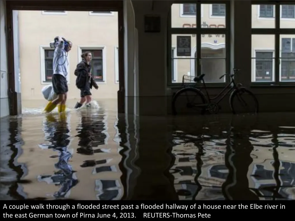 a couple walk through a flooded street past