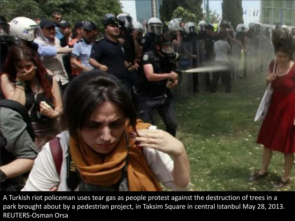 a turkish riot policeman uses tear gas as people