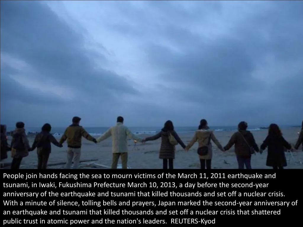 people join hands facing the sea to mourn victims