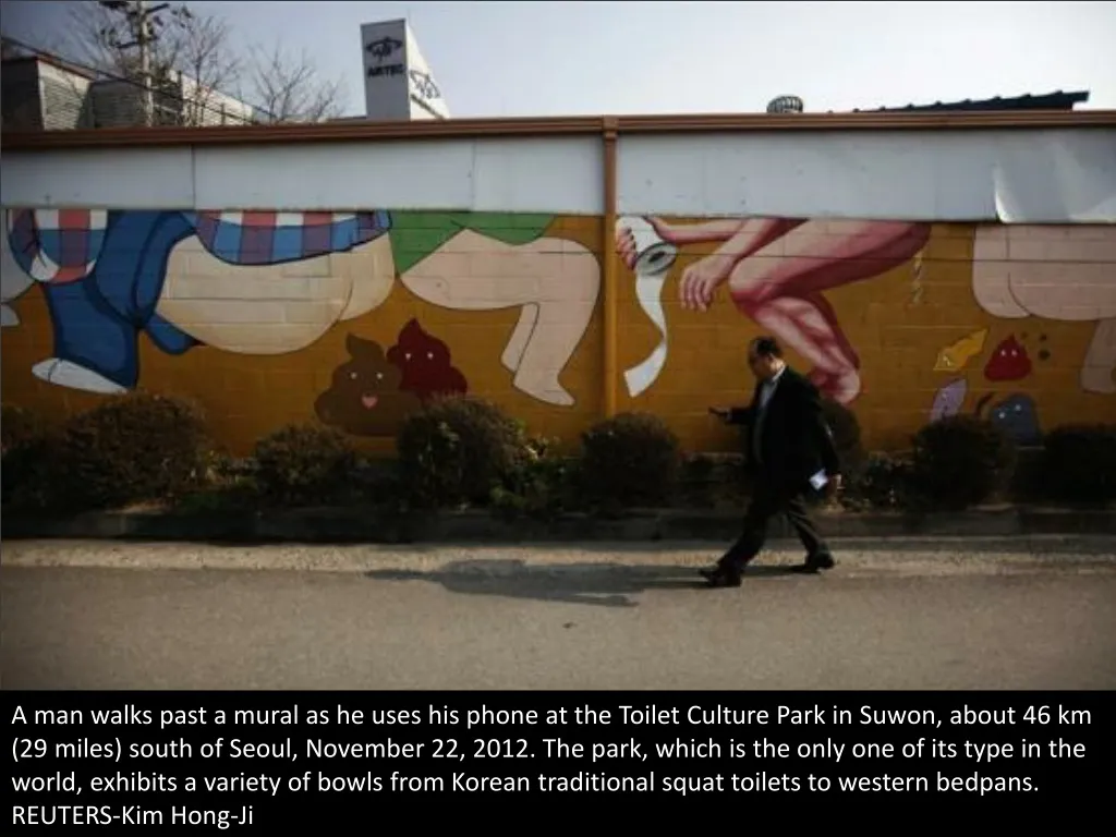 a man walks past a mural as he uses his phone
