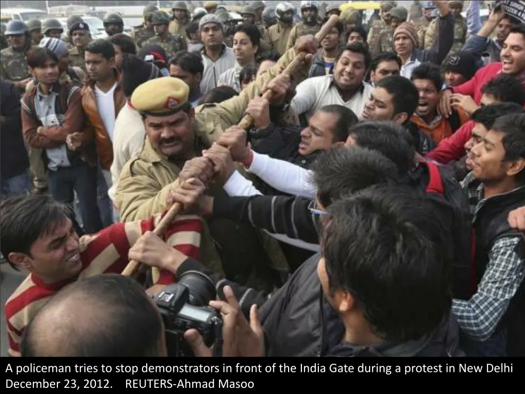 a policeman tries to stop demonstrators in front