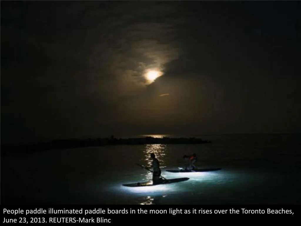 people paddle illuminated paddle boards