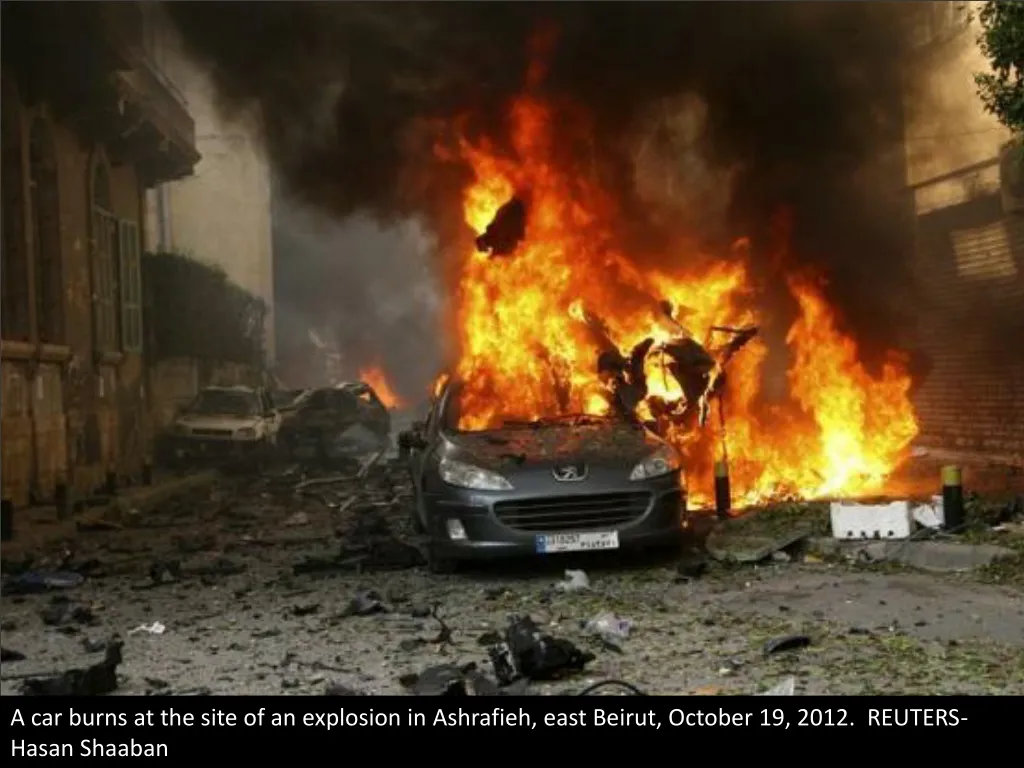 a car burns at the site of an explosion