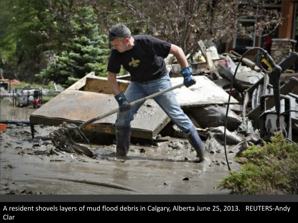 a resident shovels layers of mud flood debris