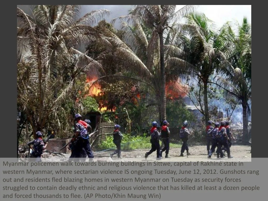 myanmar policemen walk towards burning buildings